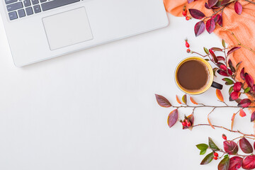 Flat lay composition with colorful autumn leaves, laptop,scarf and a cup of coffee on a white background