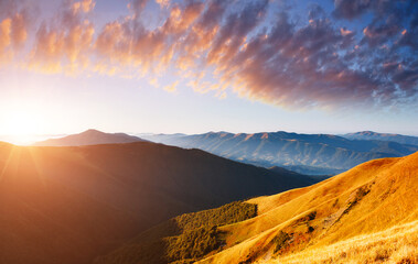 Obraz premium Picturesque sunset in the summer mountains. Evening light illuminates the valley.