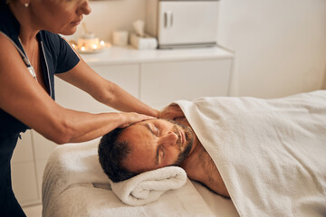 Fototapeta na wymiar Professional masseur massaging young man body at spa salon