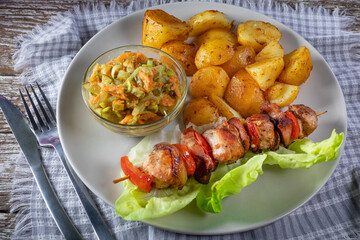 Shish kebab served with roasted potatoes and salad.