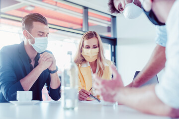Team of business people with face masks during project meeting