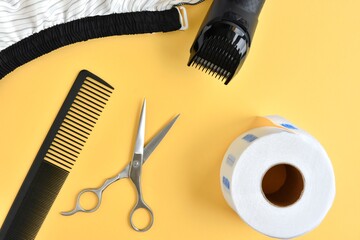 Fototapeta na wymiar Flat lay with hairdressers tools: comb, hair clipper, open scissors and space for text on yellow backdrop, selective focus 