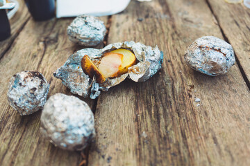 The food at the picnic. Potatoes with lard baked in foil, on a fire. Top view, on a wooden table