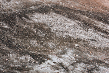 surface of a melting mountain glacier covered with stones and rubble