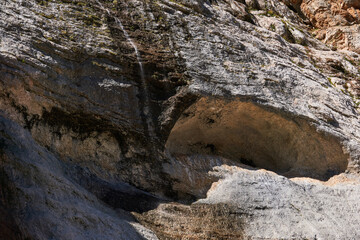 rock wall with streams of water flowing down it over the talus in the mountains