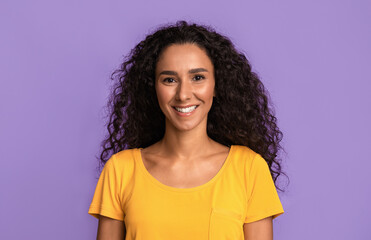 Natural beauty. Smiling woman with beautiful skin and curly hair over purple background