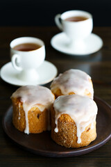 Traditional Easter kulich pastry served with white porcelain cups of tea. Wooden table, high resolution