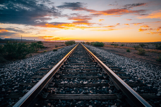 Empty train tracks going into the horizon at sunset in the desert