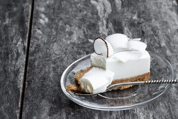 Homemade cheesecake decorated with fresh coconut flakes on rustic wooden table