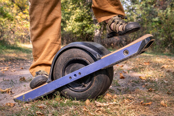 starting to ride one-wheeled electric skateboard on a forest trail, early fall scenery in Nebraska