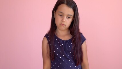 Portrait of a sad little girl pink background