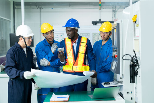 Multiethnic industrial engineers have to consult with technician while using a blueprints. Supervisor, Worker with hard hat working in manufacturing factory on business day. Concept of race equality.
