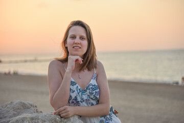 Fototapeta na wymiar Mujer joven paseando en la playa a la puesta de sol