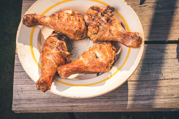 Fried chicken legs in a plate on a wooden table/Fried chicken legs in a plate on a wooden table. Top view. Sanny day.