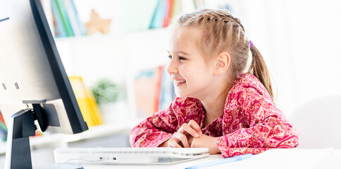 Happy little girl looking at computer screen