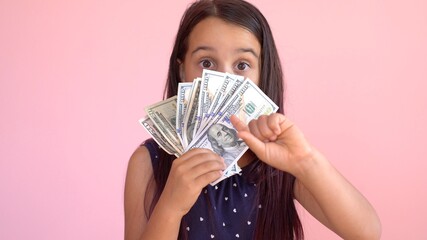 Cute little girl holding dollars, isolated over pink