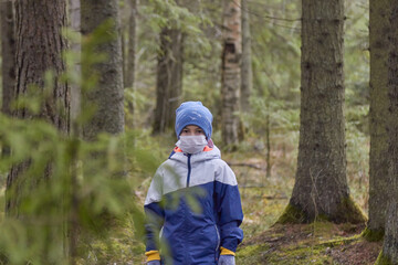 boy in protective sterile medical mask on his face looking at camera outdoors