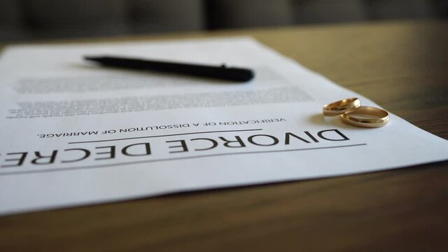 Divorce decree agreement with wedding rings on the table.