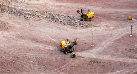 Excavator in a quarry extracting and moving stone for its transformation, top view