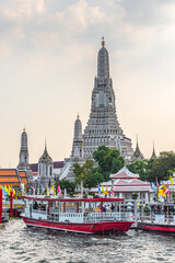 Naklejka premium Boats on Chao Phraya River and Wat Arun, The Temple of Dawn, an Important Buddhist Temple and a Famous Tourist Destination in Bangkok Yai District of Bangkok, Thailand.