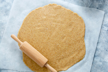 Rolled out pie or cookies dought on baking paper. Top view.