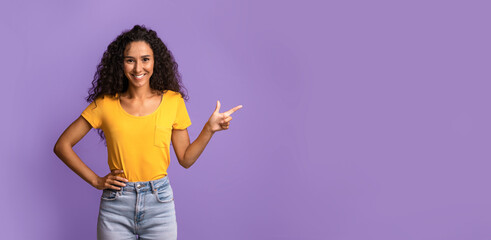 Smiling Brunette Woman Pointing Finger Aside At Copy Space Over Purple Background