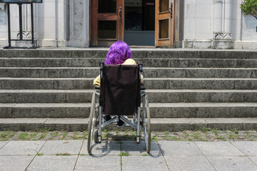 Disabled girl with purple hair in a wheelchair  in front of a stair