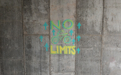 “No Limits” with a bicycle painted on a concrete wall with several up arrows, sending a positive message