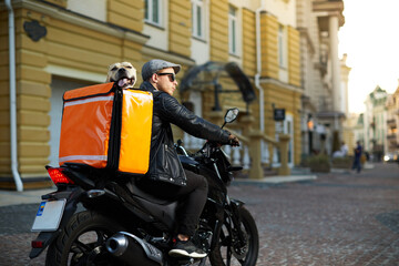 Fototapeta na wymiar Man on motorbike with the dog inside special thermo bag for delivery food on the street.Food delivery service.