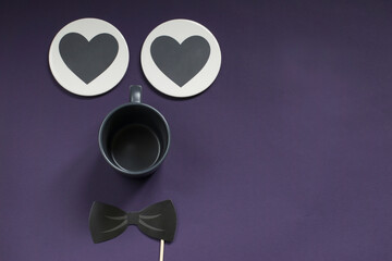 For a holiday for men. On a purple background - a bow tie, a mug of tea, two hearts for text. Postcard with copy space.