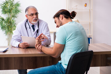 Injured young man visiting old doctor