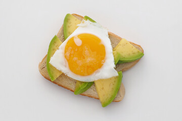 Avocado toast with fried egg on white desk.