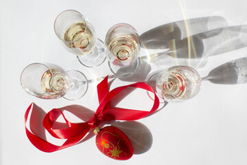 wine glass with champagne and red vintage Christmas tree ornament with ribbon on white background New Year food and drink concept 