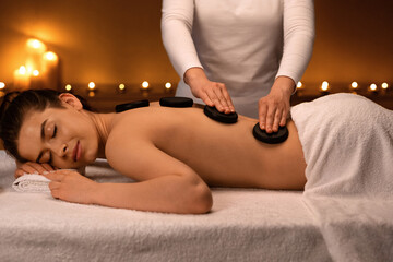 Obraz na płótnie Canvas Joyful lady having hot stone massage at luxury spa