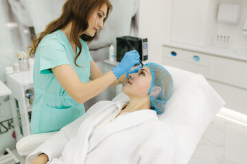 Hands of cosmetologist making preparation for face contouring plasty. Young woman gets beauty facial injections in salon. Aesthetic cosmetology