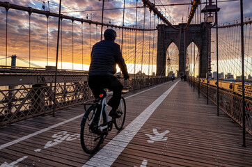 Bicyclist on Brooklyn Bridge during sunrise in New York. USA