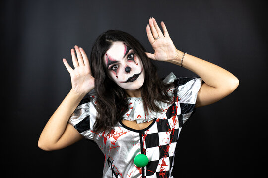 woman in a halloween clown costume over isolated black background doing scary face