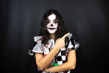 woman in a halloween clown costume over isolated black background smiling happy pointing with hand and finger to the side