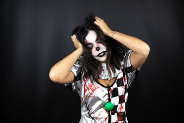 woman in a halloween clown costume over isolated black background getting crazy