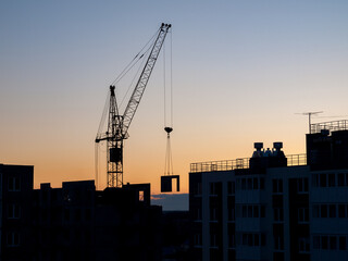 Fototapeta premium Construction crane for lifting and mounting panels, blocks in the construction of residential buildings, high-rises, skyscrapers