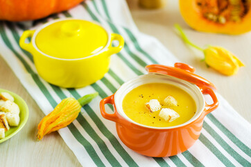 flowers and bowls with creamy pumpkin soup with vegetables, seeds and croutons. Thanksgiving Day. traditional autumn dish. soft focus