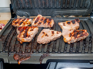 pieces of meat fried on an electric grill, steaks from meat, proper roasting of the grill