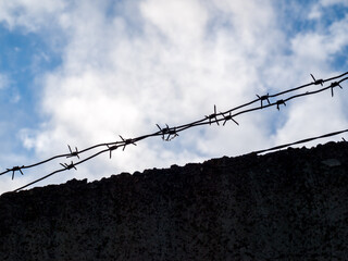 barbed wire close-up against a blue sky, the concept of incarceration, serving a sentence, restriction of freedom, isolation, crime and punishment