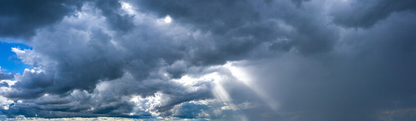 The sun's rays break through the dark stormy sky.