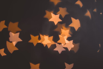 Fototapeta premium Defocused abstract bokeh lights christmas star shape at black background. orange, gold and black colors. christmas and new year concept
