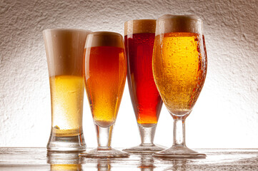 Various types of beers served in glasses and crystal mugs on rustic wooden table