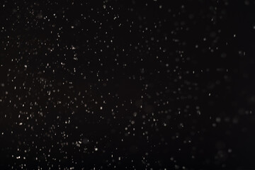 Snow abstract background. White bokeh lights isolated on black. Winter dark night sky. Defocused flying flakes pattern Christmas decorative abstract backdrop.