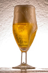 Crystal glass with cold Pilsen beer on wooden table and white background