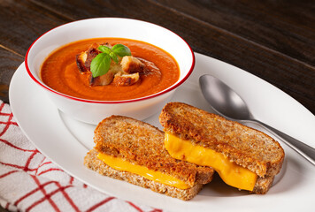 Tomato soup and grilled cheese sandwich on a wooden surface with copy space