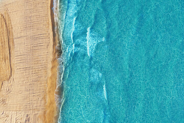 Yellow sand blue water top view. Wild beach
